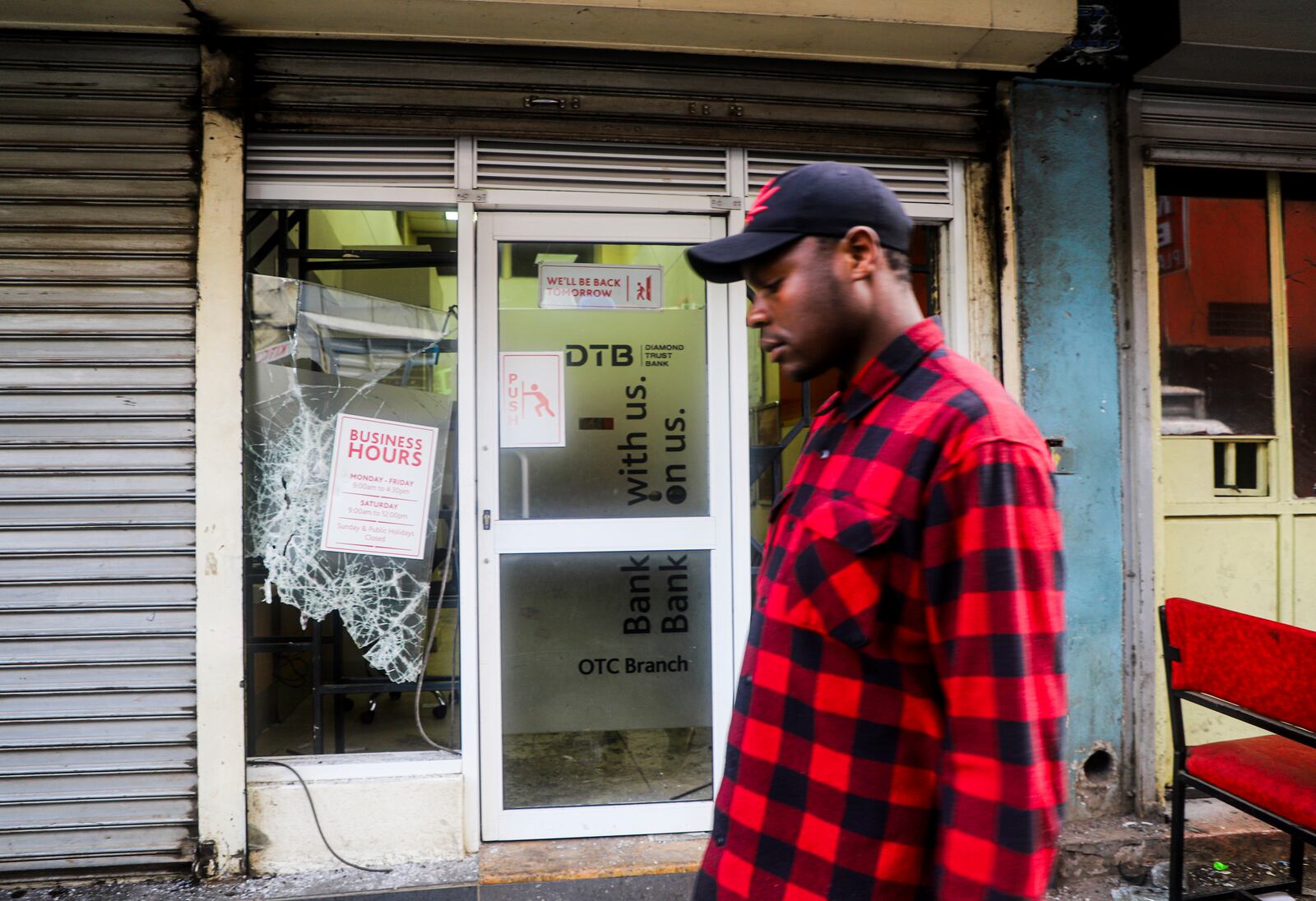 A man walks past a vandalized bank following the one-year anniversary of a deadly anti-tax demonstrations in Nairobi, Kenya, Thursday, June 26, 2025. (AP Photo/Patrick Ngugi)