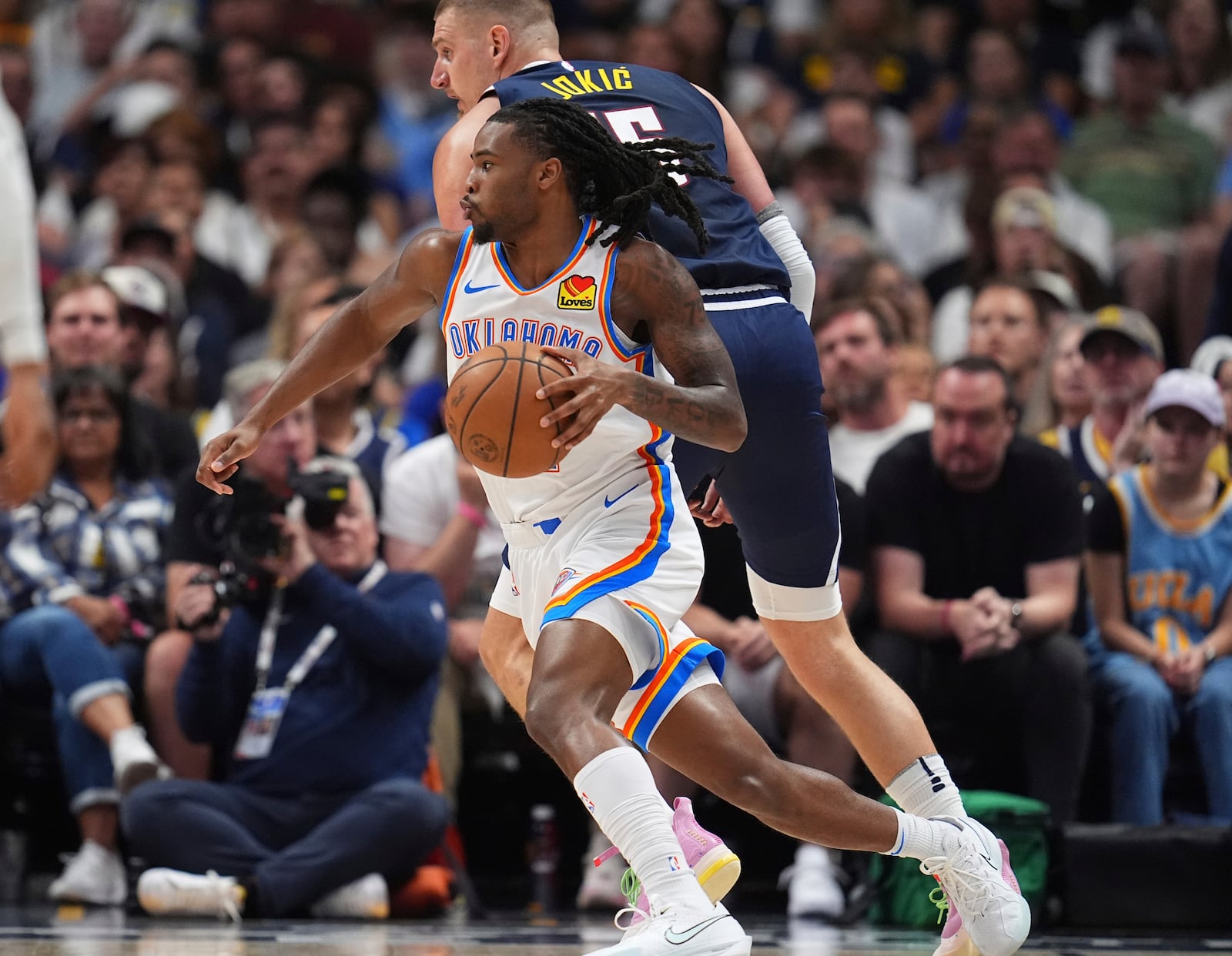 Oklahoma City Thunder guard Cason Wallace, front, drives past Denver Nuggets center Nikola Jokic, back, in the first half of Game 4 in the Western Conference semifinals of the NBA basketball playoffs Sunday, May 11, 2025, in Denver. (AP Photo/David Zalubowski)