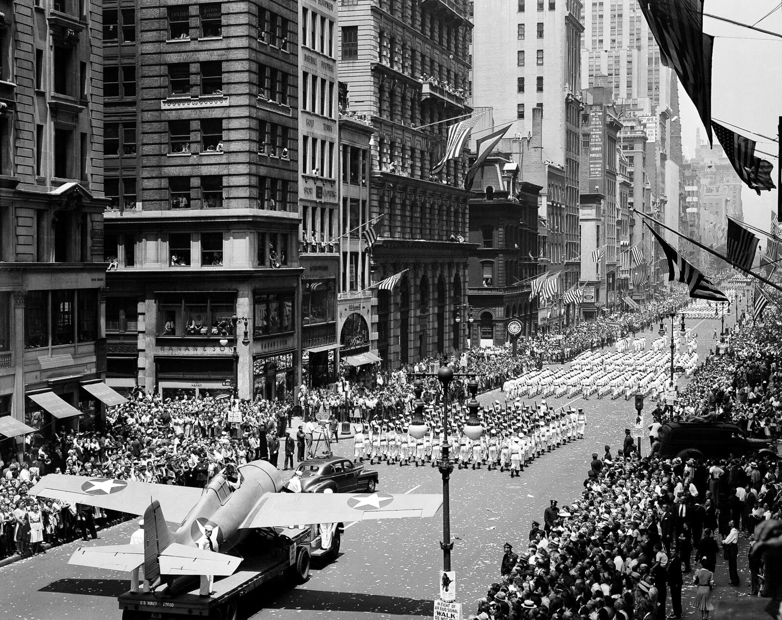FILE - Thousand of people line streets to cheer on naval units marching on Fifth Avenue in a war parade in New York, June 13, 1942. At lower left is a Grumman "Wildcat" fighter that is flown from U.S. aircraft carriers. (AP Photo, File)
