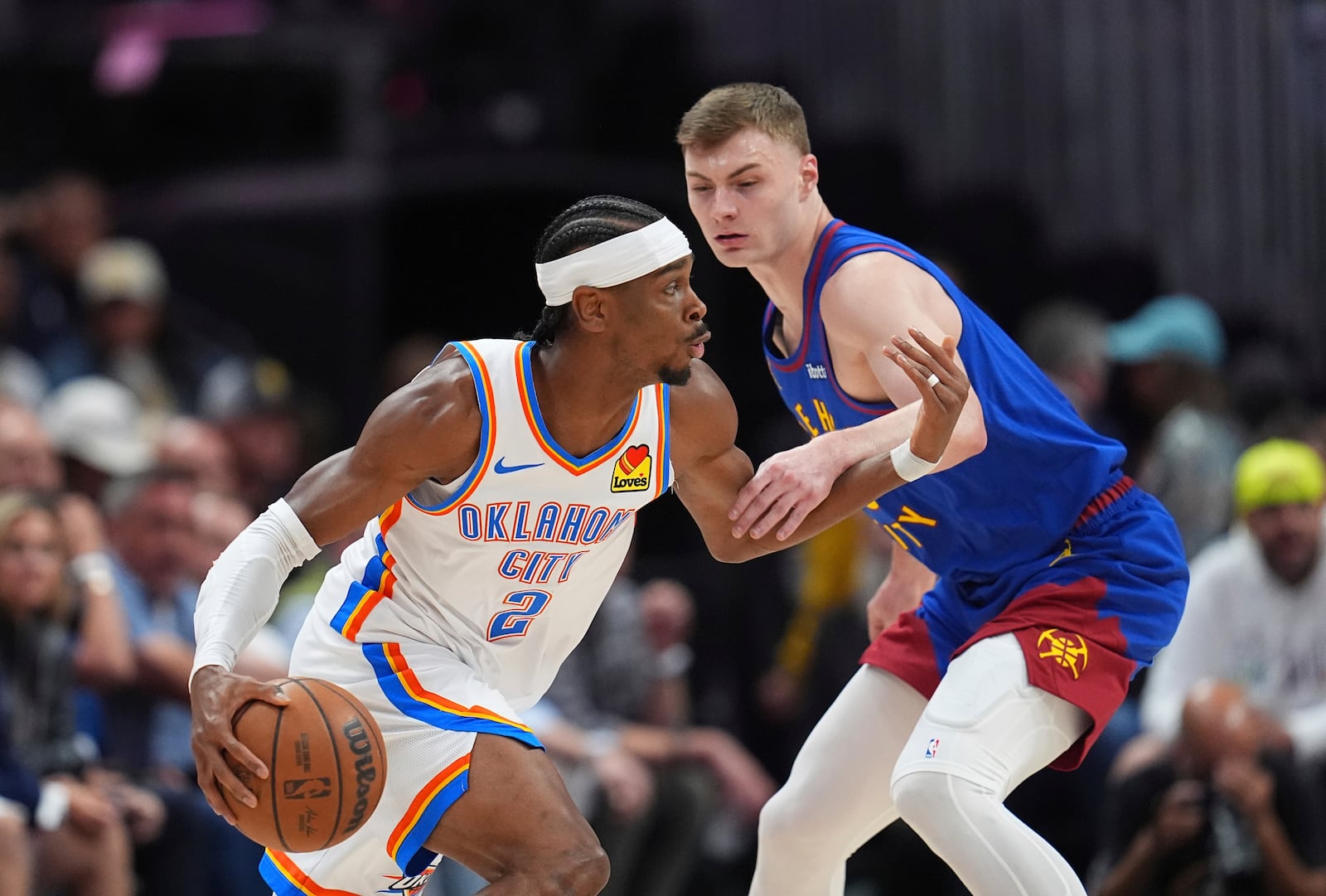 Oklahoma City Thunder guard Shai Gilgeous-Alexander, left, drives past Denver Nuggets guard Christian Braun, right, in the first half of Game 3 in the Western Conference semifinals of the NBA basketball playoffs Friday, May 9, 2025, in Denver. (AP Photo/David Zalubowski)