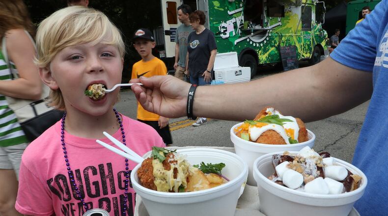 Tate VanHoose, 8, tries some of the food his father, was holding Saturday at the Springfield Rotary Gourmet Food Truck Competition in Veteran’s Park. BILL LACKEY/STAFF