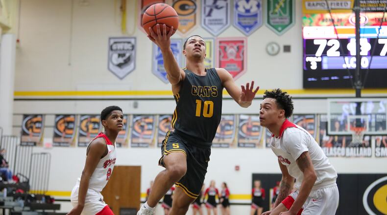 Cutline: Springfield High School junior Delian Bradley drives through West Carrollton's DeShawn Ferguson (right) and Javen Vaughn (left)
during their game on Tuesday night at Centerville High School. Bradley scored a career-high 24 points in the victory. Michael Cooper/CONTRIBUTED