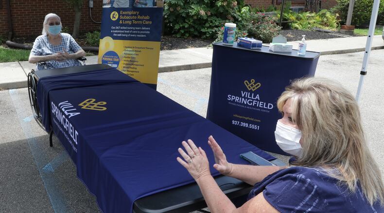 Sheryl Hahn, right, talks about finally getting to see her mother, Mary Worley, who's been a patient at Villa Springfield Friday. They had to social distance in the parking lot and kept a table between them but Sheryl said it was worth it. BILL LACKEY/STAFF