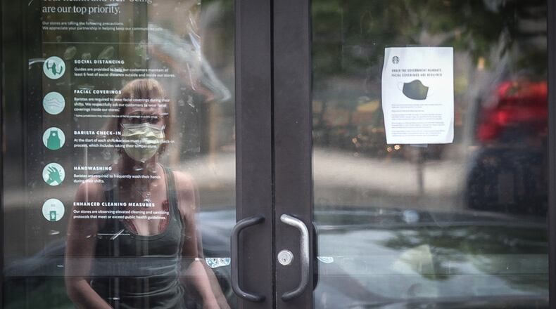 A woman wearing a mask is about to exit Starbucks on Far Hills Avenue. in Oakwood on Monday, July 20, 2020. Many large retailers are now requiring that customers join their employees in wearing face masks to stop the spread of the coronavirus. Starbucks, Best Buy and Kroger are among retailers that have announced mandatory masks nationwide in recent days. Starbucks and Best Buy started requiring that customers wear masks on July 15.  JIM NOELKER/STAFF