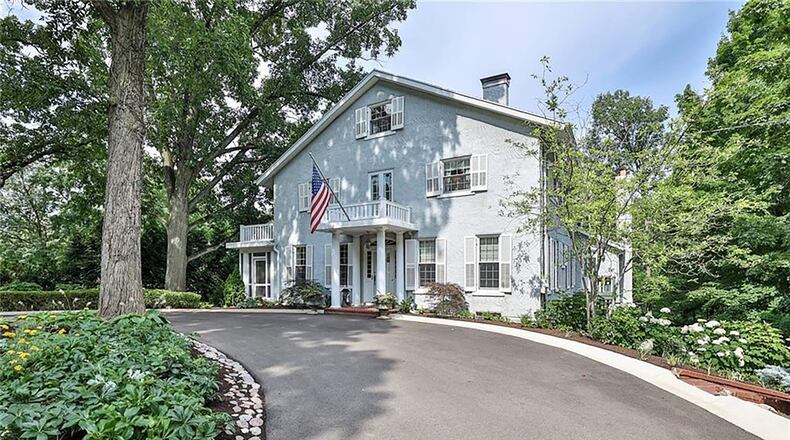 The circular driveway connects the road to the front of the home, which has a covered portico and brick porch.
