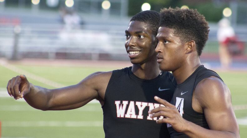 Wayne teammates Justin Harris (left) and Zarik Brown celebrate after they helped win the 1,600-meter relay and clinch the team title over Centerville at Friday’s Division I regional track and field meet at Wayne High School. JEFF GILBERT / CONTRIBUTED
