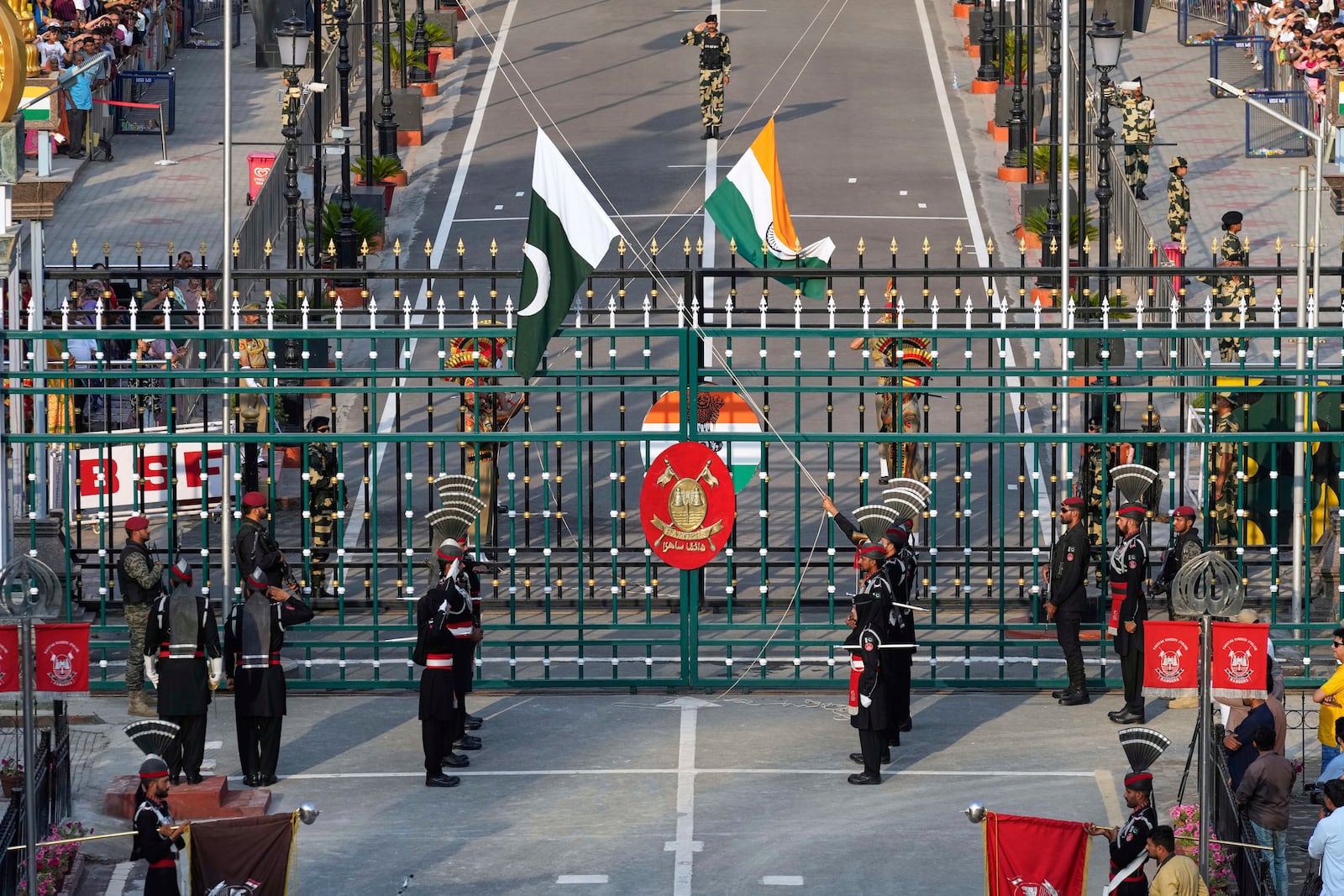 Pakistan's Rangers soldiers, in black, and Indian Border Security Forces soldiers, behind the gate, lower their flags during a daily closing ceremony at the Wagah, a joint post on the Pakistan and India border, near Lahore, Pakistan, Monday, May 5, 2025. (AP Photo/K.M. Chaudary)