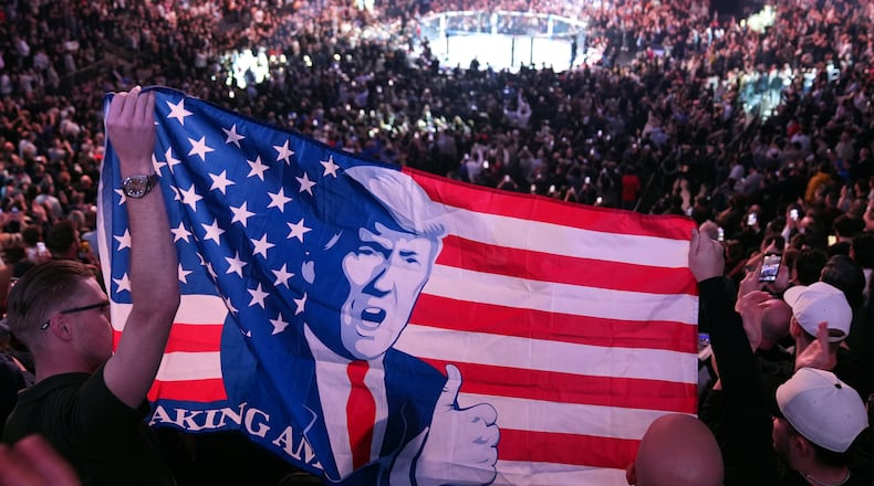 FILE - People hold a flag as President-elect Donald Trump arrives at UFC 309 at Madison Square Garden, Nov. 16, 2024, in New York. (AP Photo/Evan Vucci, File)