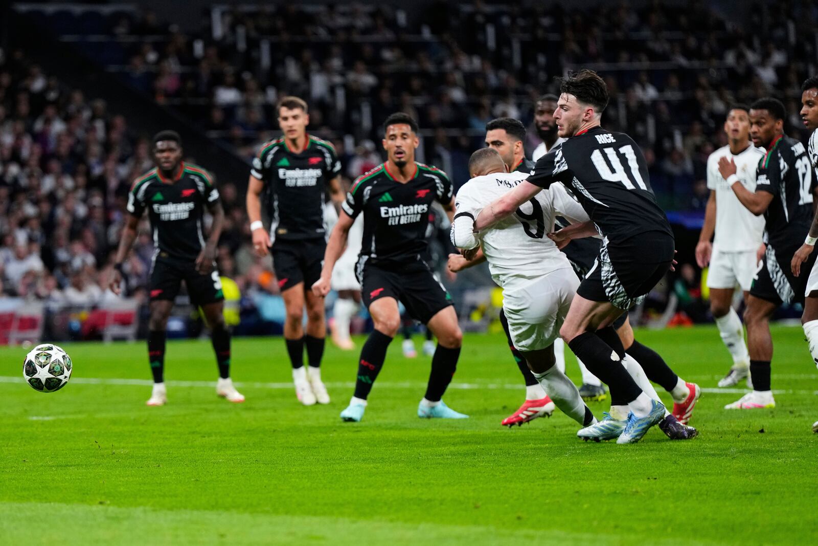 Arsenal's Declan Rice, center right, grabs Real Madrid's Kylian Mbappe in the box during the Champions League quarterfinals second leg soccer match between Real Madrid and Arsenal at the Santiago Bernabeu stadium in Madrid, Wednesday, April 16, 2025. (AP Photo/Manu Fernandez)