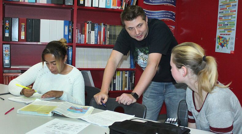 Springfield High School International Baccalaureate teacher Matthew Rudy helps (left) Jasmine Owens and Gracie Vandegrift with their capstone project. JEFF GUERINI/STAFF