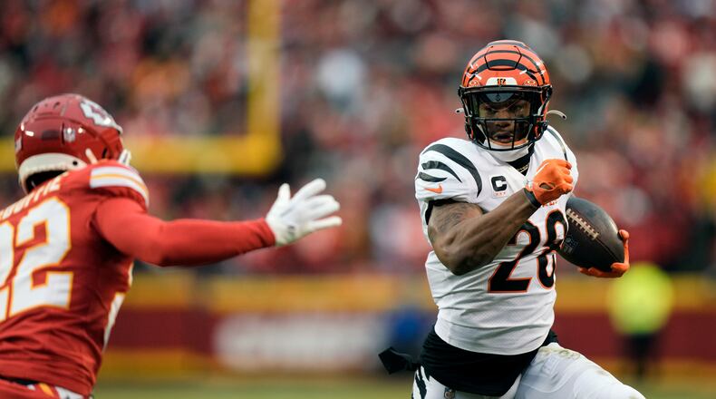 Cincinnati Bengals running back Joe Mixon (28) runs with the ball as Kansas City Chiefs cornerback Trent McDuffie (22) defends during the first half of an NFL football game Sunday, Dec. 31, 2023, in Kansas City, Mo. (AP Photo/Charlie Riedel)