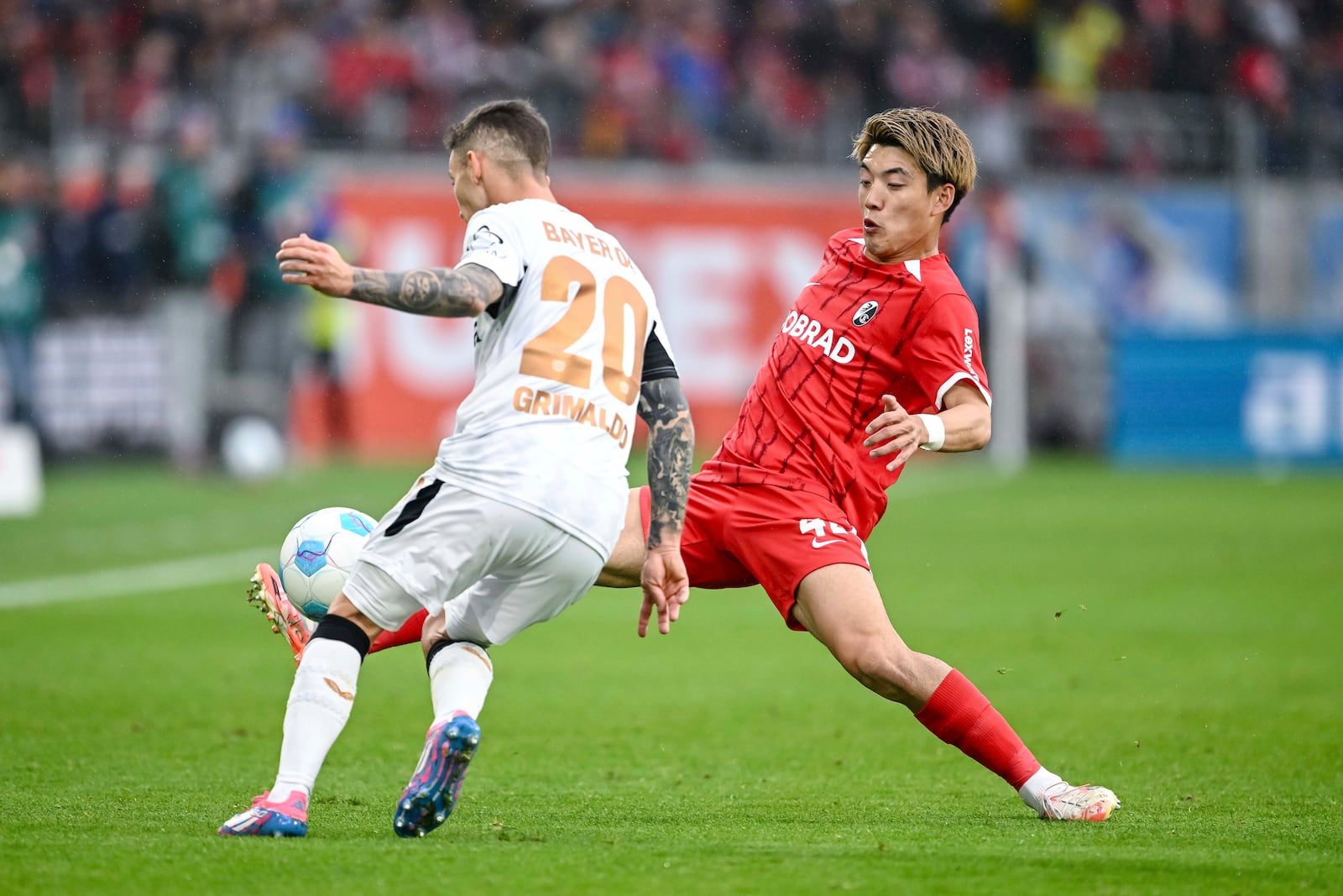 Leverkusen's Alejandro Grimaldo, left, vies for the ball with Freiburg's Ritsu Doan, during the German Bundesliga soccer match between, SC Freiburg and Bayer Leverkusen, at Europa-Park Stadium, in Freiburg im Breisgau, Germany, Sunday, May 4, 2025. (Harry Langer/dpa via AP)