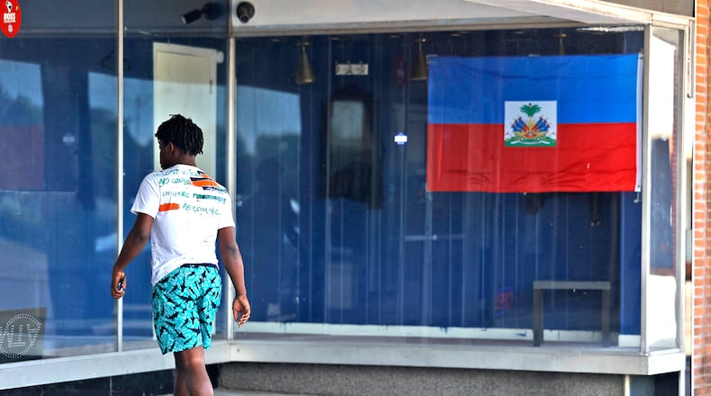 A man walks past a Haitian flag as he enters a Haitian-owned business in the Southern Village Shopping Center Monday, July 15, 2024. BILL LACKEY/STAFF