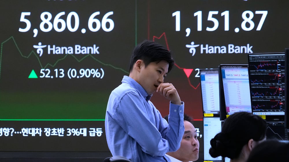 A currency traders reacts near a screen showing the Korea Composite Stock Price Index (KOSPI), left, and the foreign exchange rate between U.S. dollar and South Korean won at the foreign exchange dealing room of the Hana Bank headquarters in Seoul, South Korea, Monday, Feb. 23, 2026. (AP Photo/Ahn Young-joon)