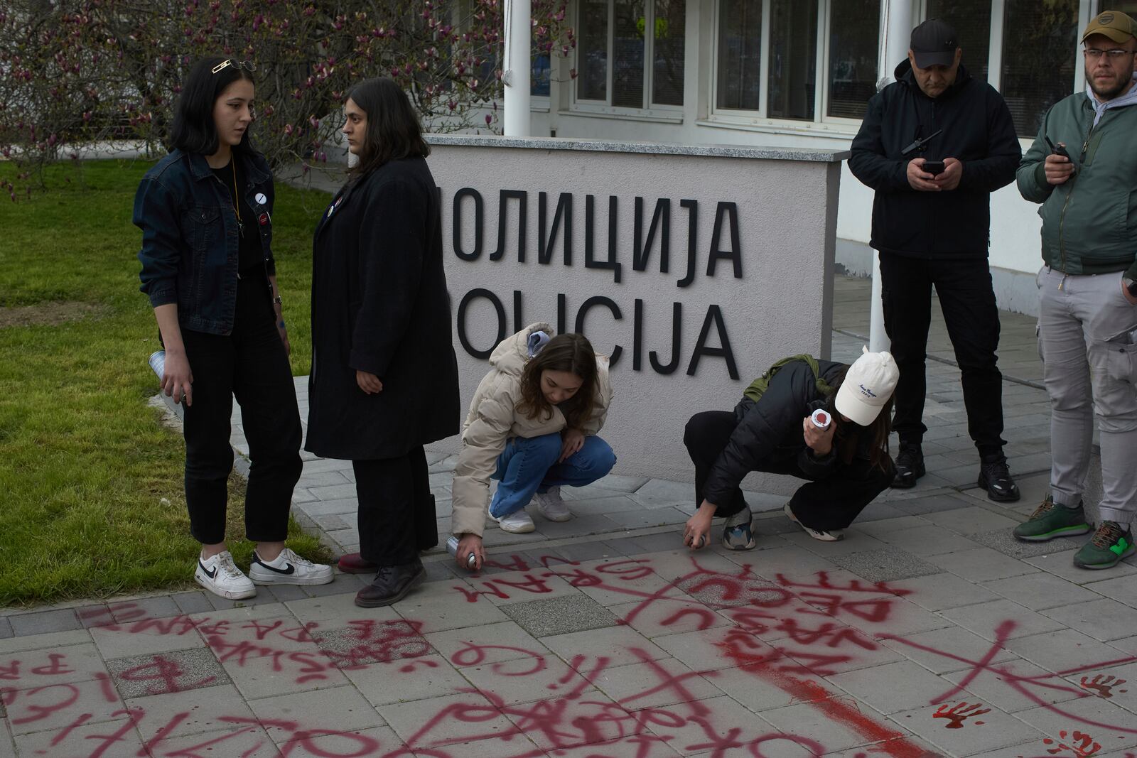 People use red spray paint in front of a local police station during an anti-corruption protest led by university students in the southwestern town of Novi Pazar, Serbia, Saturday, April 12, 2025. (AP Photo/Marko Drobnjakovic)