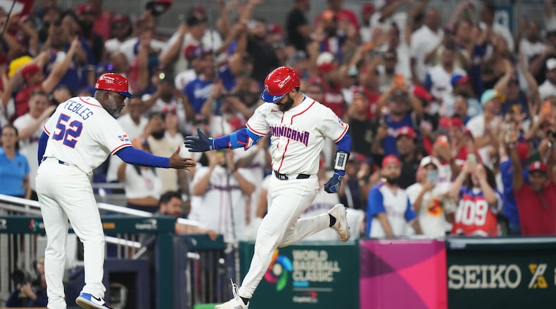 Dominican Republic's Austin Wells is congratulated by third base coach Carlos Febles as he heads for home after hitting a three-run home run to end the game early in the seventh inning of a World Baseball Classic quarterfinal game against South Korea, Friday, March 13, 2026, in Miami. (AP Photo/Lynne Sladky)