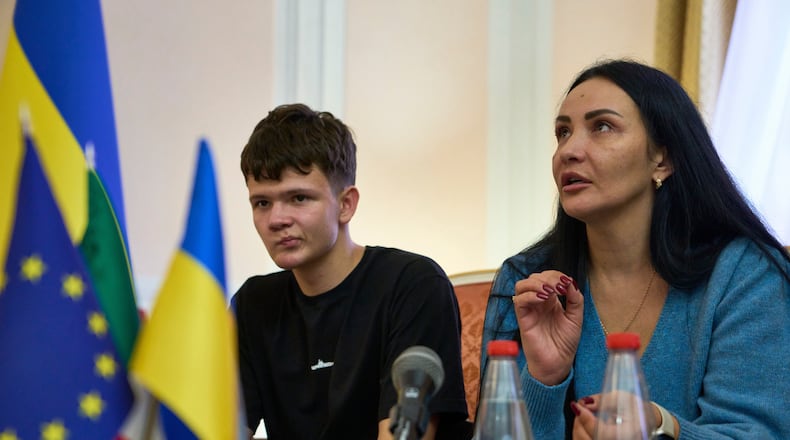 Mark Razvozov, left, listens to his mother Yukiia Dvornychenko, during a press conference on the return of Ukrainian children and civilians taken by Russia during the three-and-a-half-year war, at the Embassy of Ukraine in Italy, in Rome, Wednesday, Nov. 19, 2025. (AP Photo/Domenico Stinellis)
