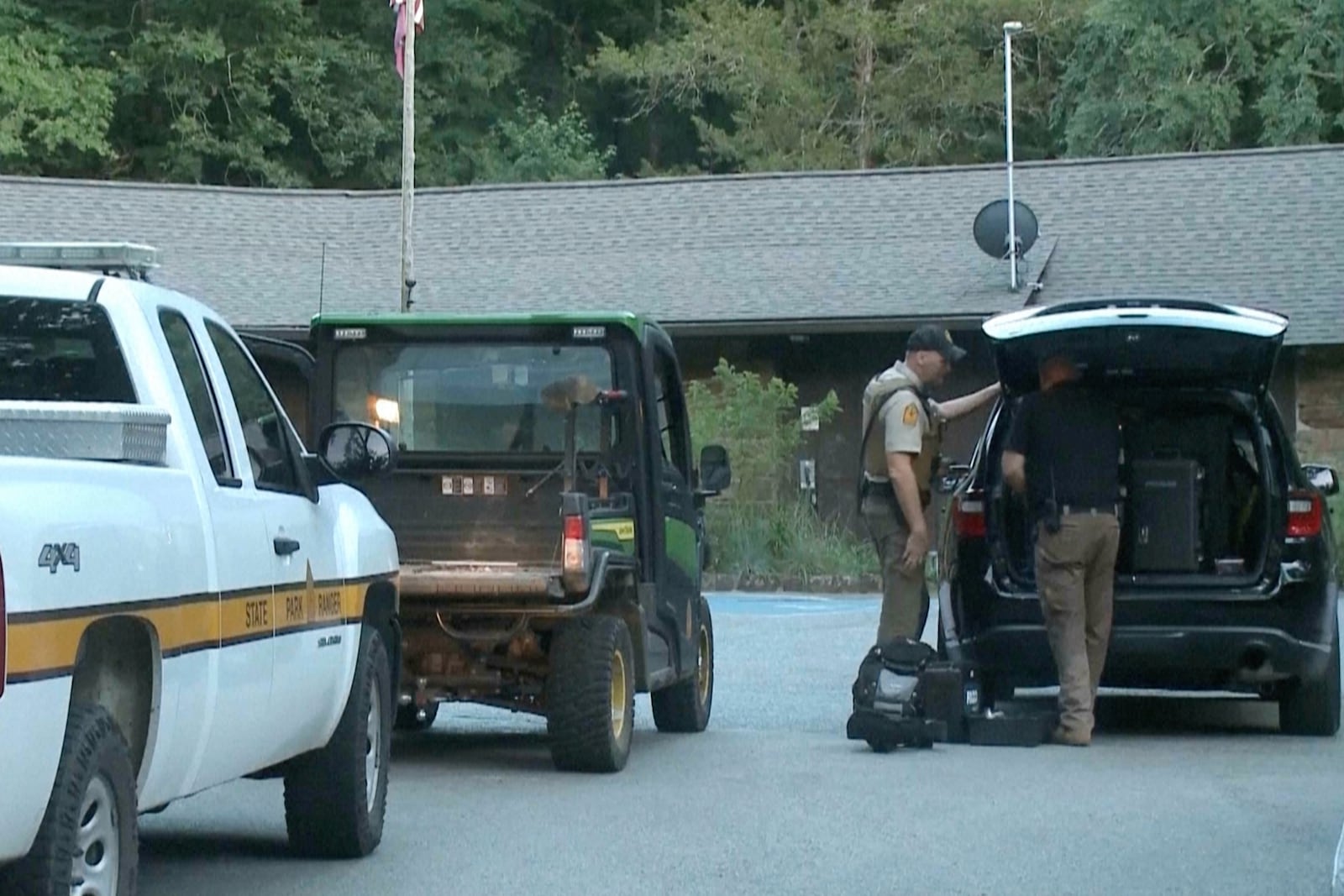 In this image made from video taken on Saturday, July 26, 2025, provided by KHBS/KHOG, law enforcement officers investigate the deaths of a couple who were attacked while on a wooded walking trail with their two young daughters at Devil's Den State Park in West Fort, Ark. (KHBS/KHOG via AP)