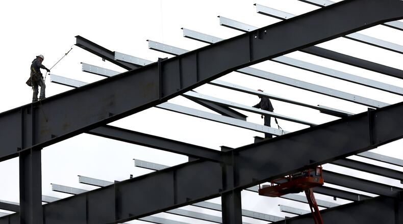 Construction workers guide a roof beam into place as work continues on the second phase of the Topre plant. Bill Lackey/Staff