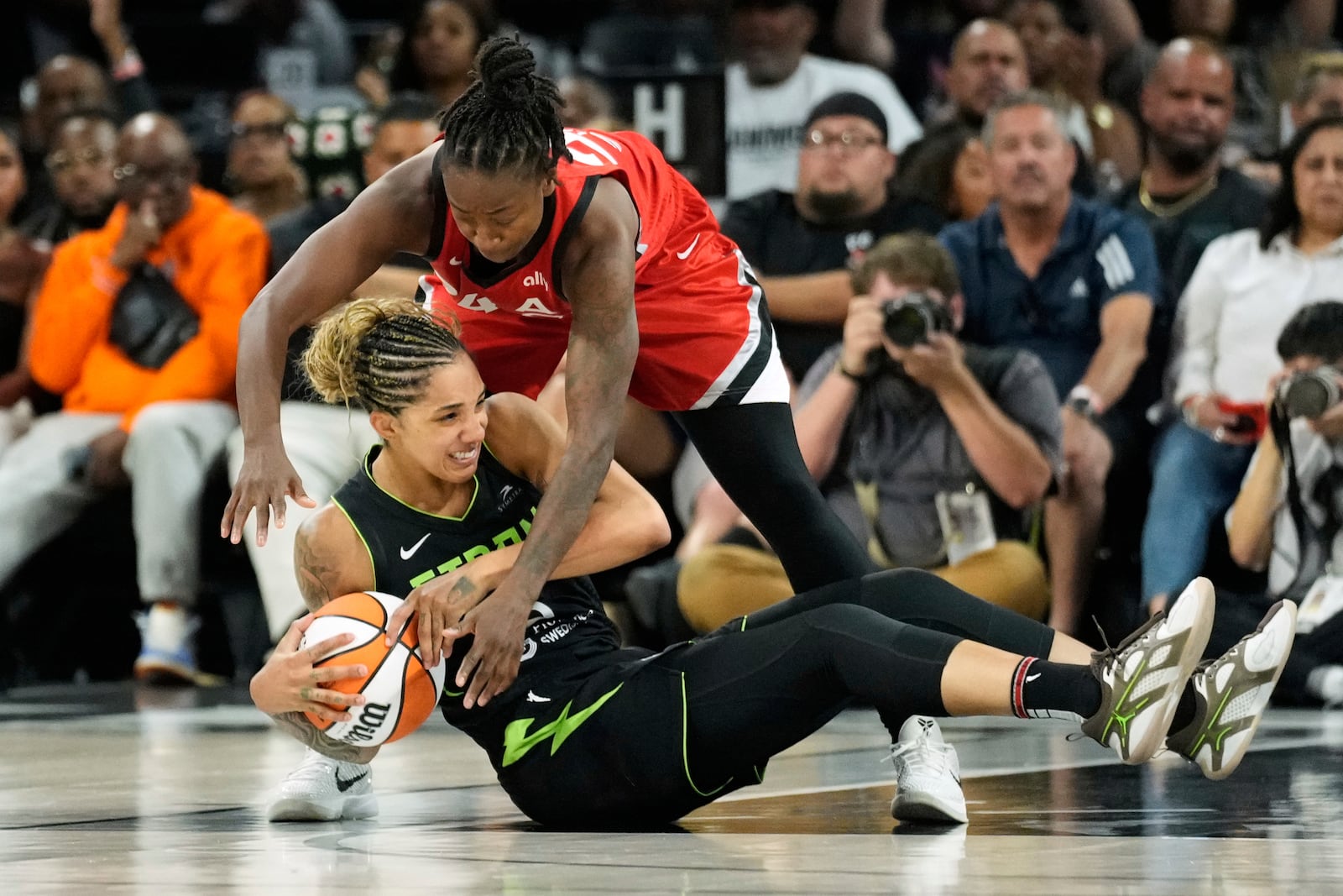 Seattle Storm forward Gabby Williams, left, and Las Vegas Aces guard Jewell Loyd scramble for the ball during the second half of a WNBA basketball game Friday, June 20, 2025, in Las Vegas. (AP Photo/John Locher)