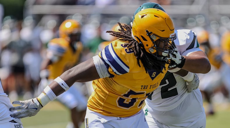 Springfield High School defensive tackle Royce Rogers plows through the interior line of Louisville Trinity during their game earlier this month in Springfield. MICHAEL COOPER / STAFF