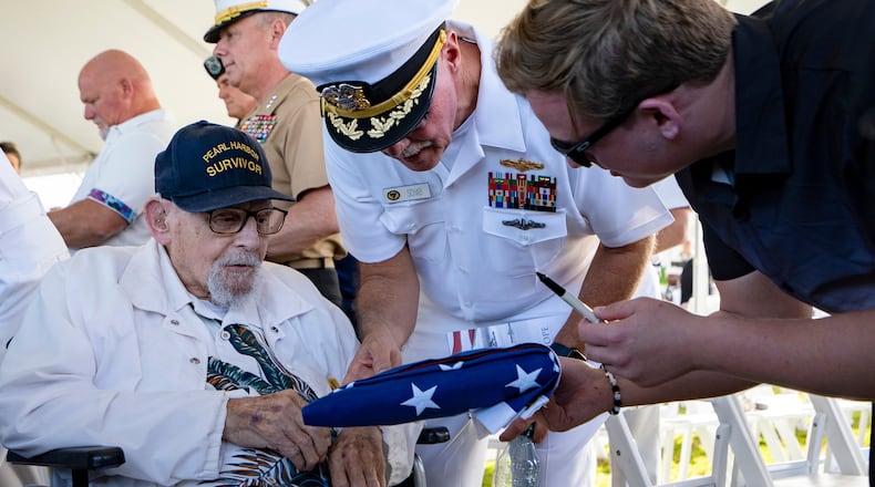 FILE - An attendee asks Pearl Harbor survivor Ira "Ike" Schab, 103, to sign an U.S. flag during the 82nd Pearl Harbor Remembrance Day ceremony on Thursday, Dec. 7, 2023, at Pearl Harbor in Honolulu, Hawaii. (AP Photo/Mengshin Lin, File)