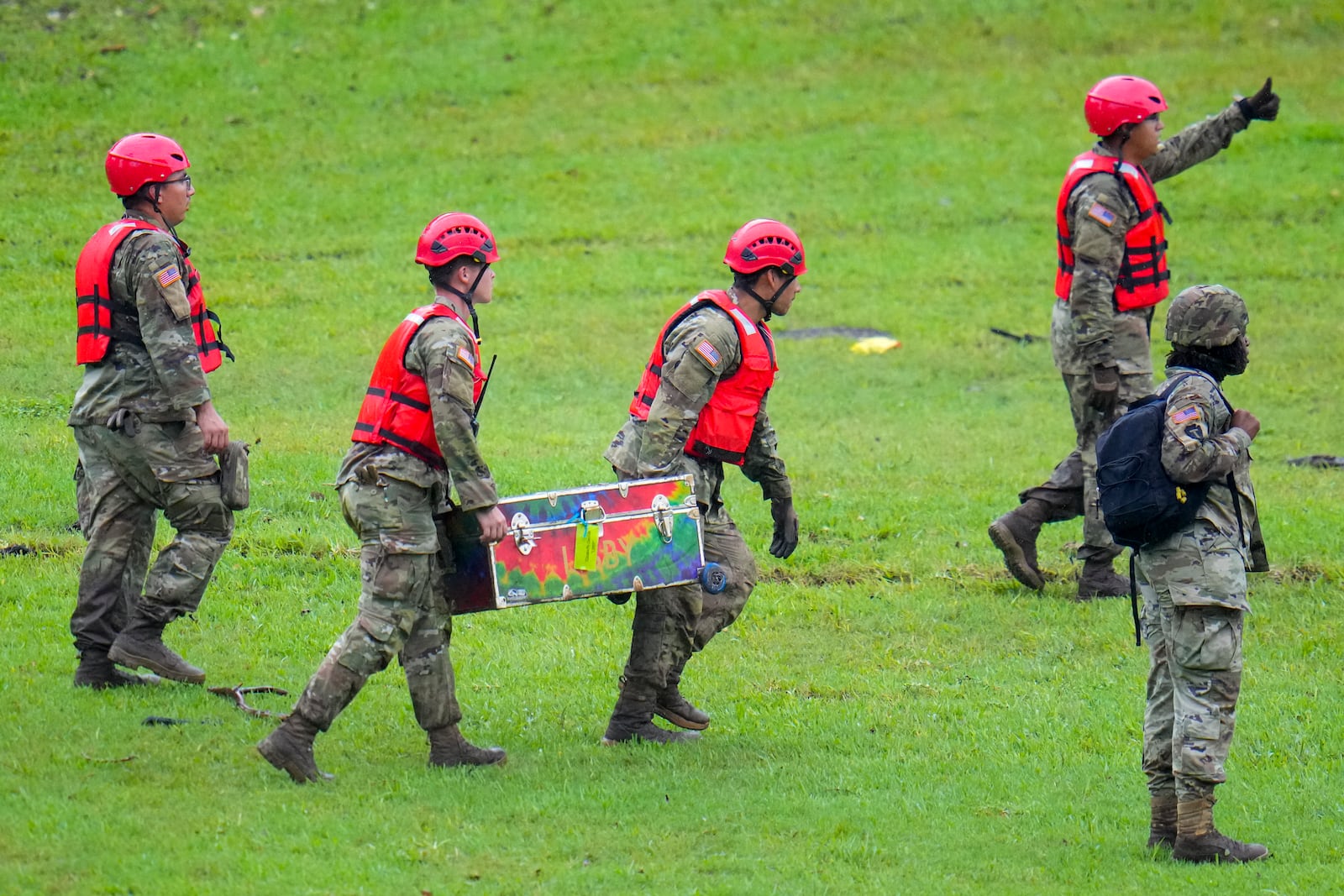 Military personnel carry a camp trunk salvaged down river from Camp Mystic along the Guadalupe River after a flash flood swept through the area Sunday, July 6, 2025, in Hunt, Texas. (AP Photo/Julio Cortez)