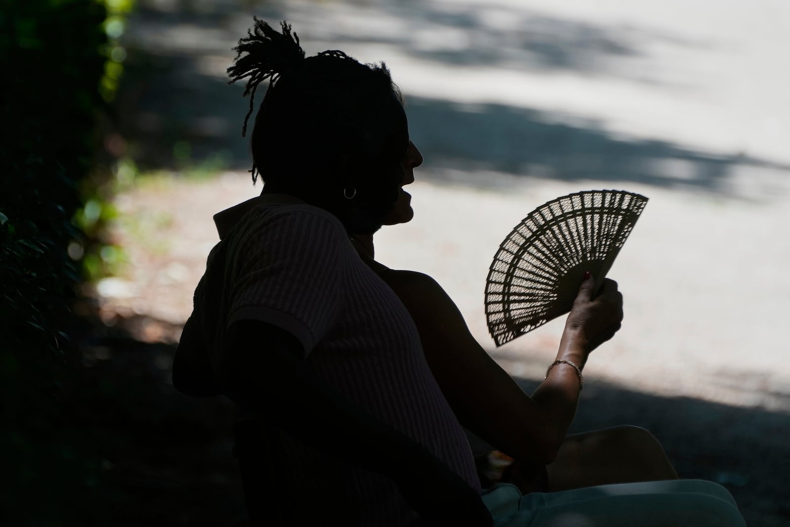 FILE - A man fans himself as he rests on a hot day in Retiro Park in Madrid, Spain, June 28, 2025. (AP Photo/Paul White, File)