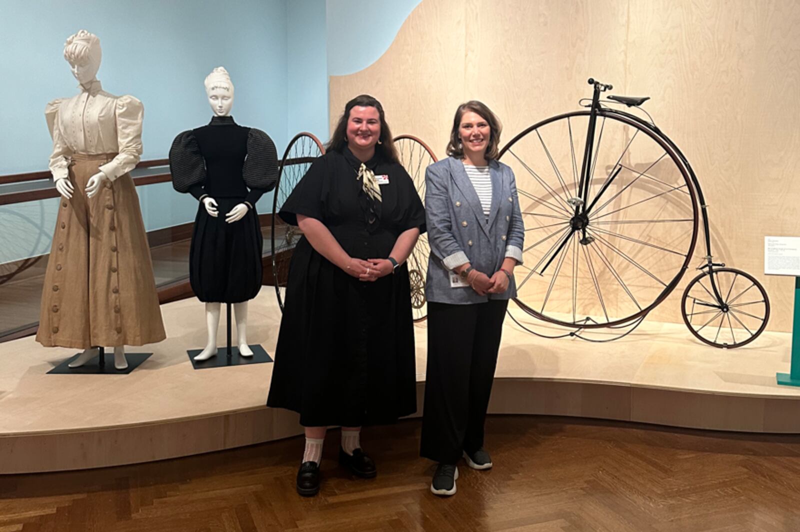 Amy Dehan, (right) the Cincinnati Art Museum's curator of Decorative Arts and Design, stands with Mackenzie Strong (left), curatorial assistant, at the entrance to "Cycle Thru! The Art of the Bike." CONTRIBUTED