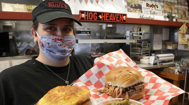 Nichole Rowland, an employee at Rudy Smokehouse, with a tray of food Friday. Rudy's is one of several local restaurants that will be providing restaurant meals to older adults effected by COVID-19. BILL LACKEY/STAFF