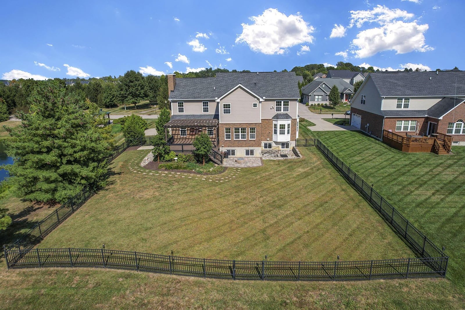 The home is surrounded by a metal fence and has a wood deck with pergola and a paver patio with firepit. CONTRIBUTED