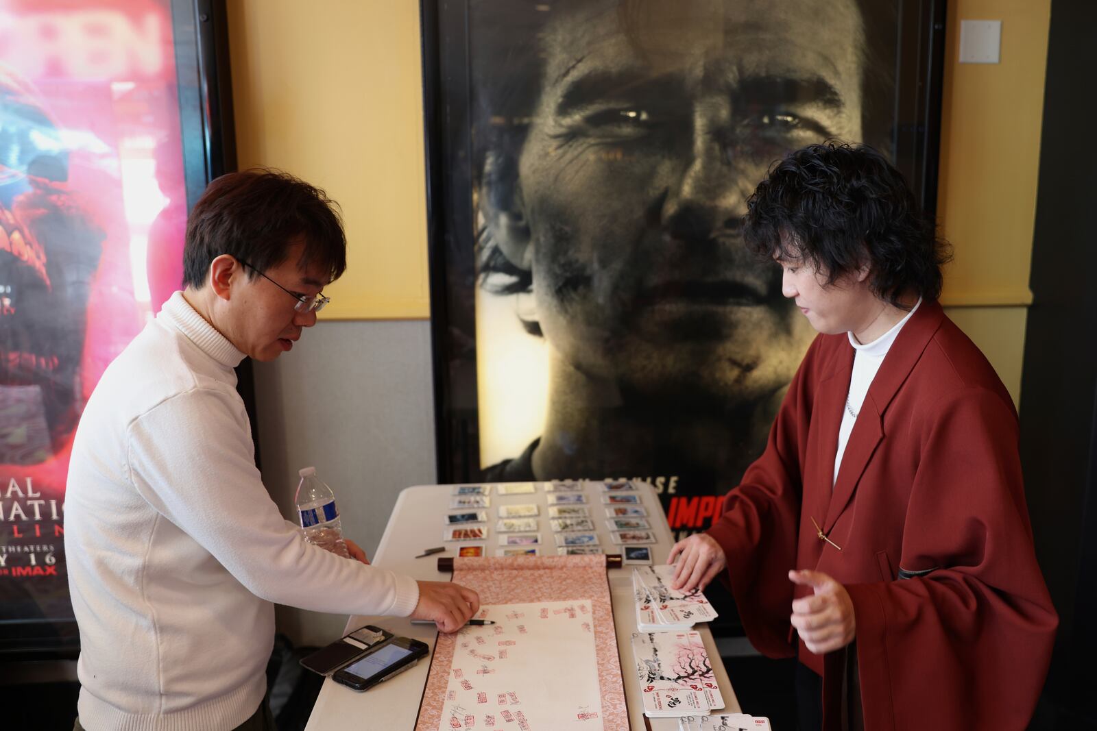 This photo provided by Jialin Sun shows people signing their names onto a Chinese scroll and to get tickets styled like traditional Chinese paintings, with the help of organizer Sun Bohan, at a movie screening of Ne Zha 2 at an IMAX screen in Columbia Md., on March 1. (Jialin Sun via AP)