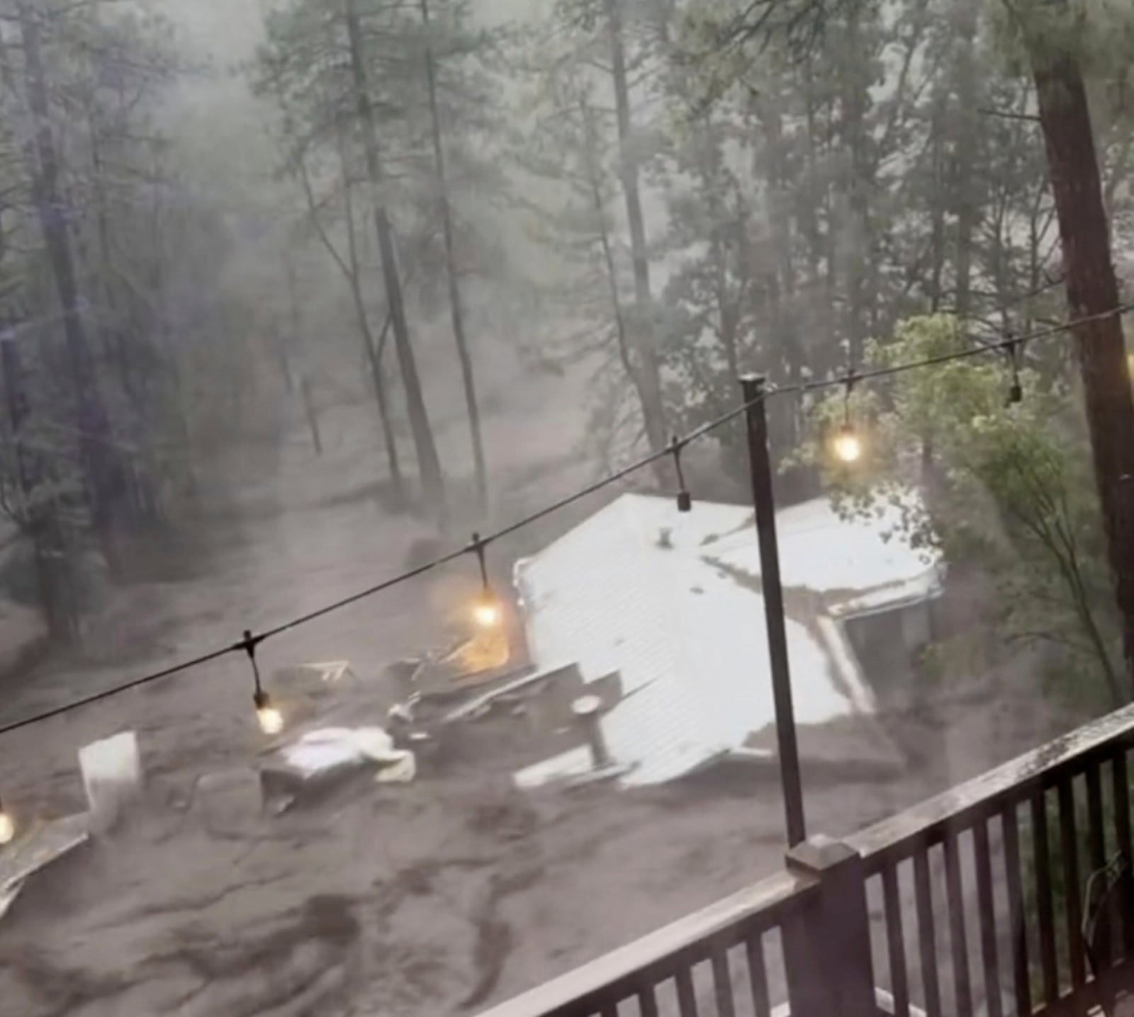 In this image taken from video, a house carried away by flash flooding is seen behind a house in Ruidoso, N.M., Tuesday, July 8, 2025. (Kaitlyn Carpenter via AP)