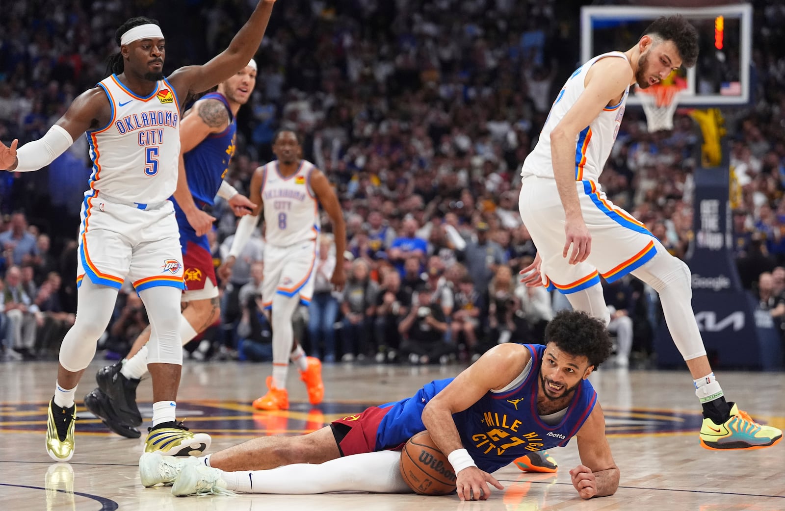 Denver Nuggets guard Jamal Murray, front, recovers a loose ball as Oklahoma City Thunder guard Luguentz Dort, back left, and forward Chet Holmgren defend in overtime of Game 3 in the Western Conference semifinals of the NBA basketball playoffs, Friday, May 9, 2025, in Denver. (AP Photo/David Zalubowski)