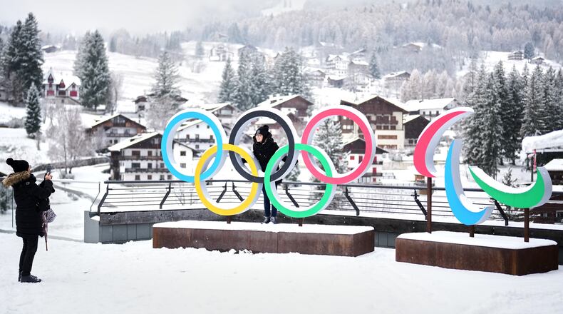 FILE - People take photos in front of the Milan Cortina Winter Olympics and Paralympics rings, in Cortina D'Ampezzo, Thursday, Nov. 20, 2025. (AP Photo/Andrew Medichini, File)