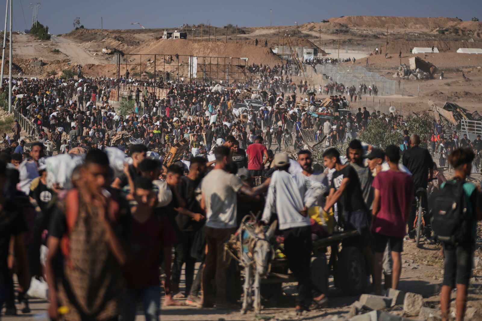Palestinians carry humanitarian aid packages near the Gaza Humanitarian Foundation distribution center operated by the U.S.-backed organization in Khan Younis, southern Gaza Strip, Thursday, June 26, 2025. (AP Photo/Abdel Kareem Hana)