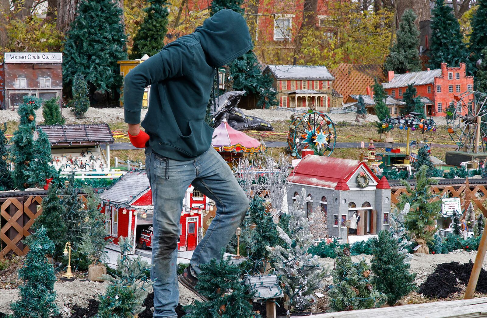Like a scene from a Godzilla movie, Jack Moore looks like a giant as he gingerly walks through the miniature village at Clifton Mill Monday, Nov. 20, 2023. The staff at Clifton Mill has been busy putting the final touches on their Christmas light display, which starts Friday, Nov. 24th and runs through the holidays. This year, they've added even more lights bringing the total to over five million lights. BILL LACKEY/STAFF