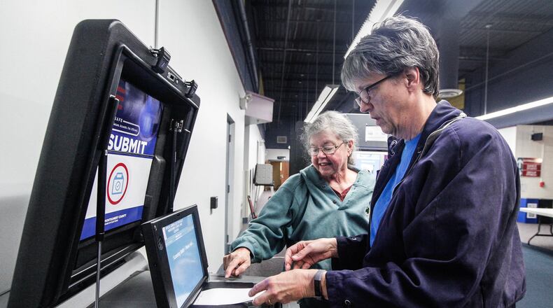 Archive photo: Washington Twp. voter Linda Hunter feeds her ballot into a machine with the help of poll worker Terrie Gutwein at the Washington Twp. Recreation Center.  New poll workers are being sought due to concerns of the coronavirus. CHRIS STEWART / STAFF