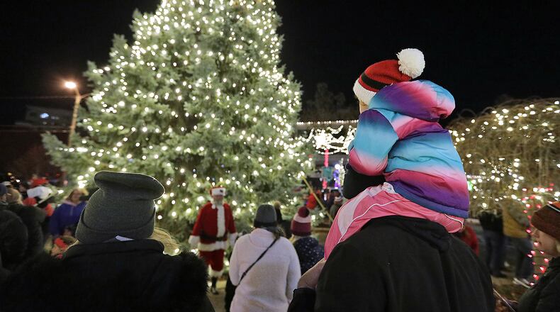 A young girl rides on her father's shoulders as she waits to see Santa at the Grand Illumination in downtown Springfield. BILL LACKEY/STAFF