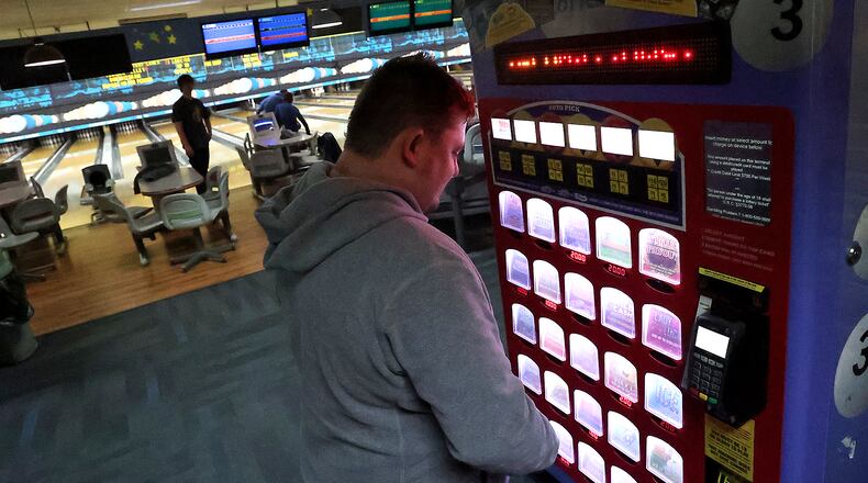 Brandon Oty looks over the Ohio Lottery instant games in a kiosk at Victory Lanes bowling alley in Springfield. BILL LACKEY/STAFF