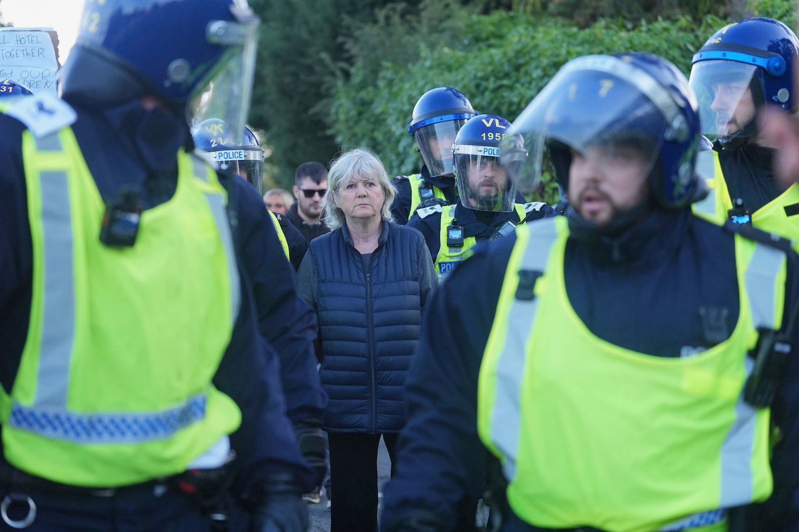 Police officers escort a woman away from a demonstration for her own safety, after a protest outside the Bell Hotel in Epping, northeast of London, Sunday, July 20, 2025. (Yui Mok/PA via AP)