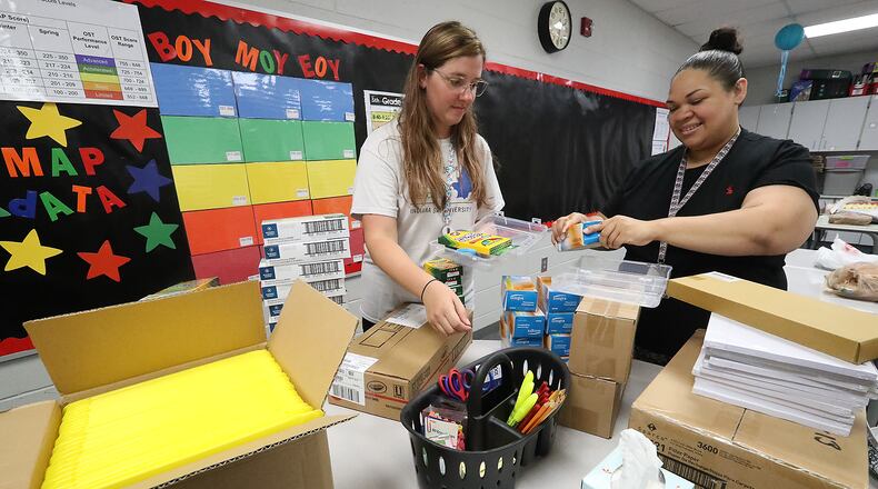 The Springfield City School District will provide school supplies to students in kindergarten through eighth grades for the fourth year in a row. In this file photo, Fulton Elementary School teacher's Mikyla Timmerman, left, and Kathleen Haley put school supplies into plastic boxes for each student as they prepared for school to start. FILE/BILL LACKEY/STAFF