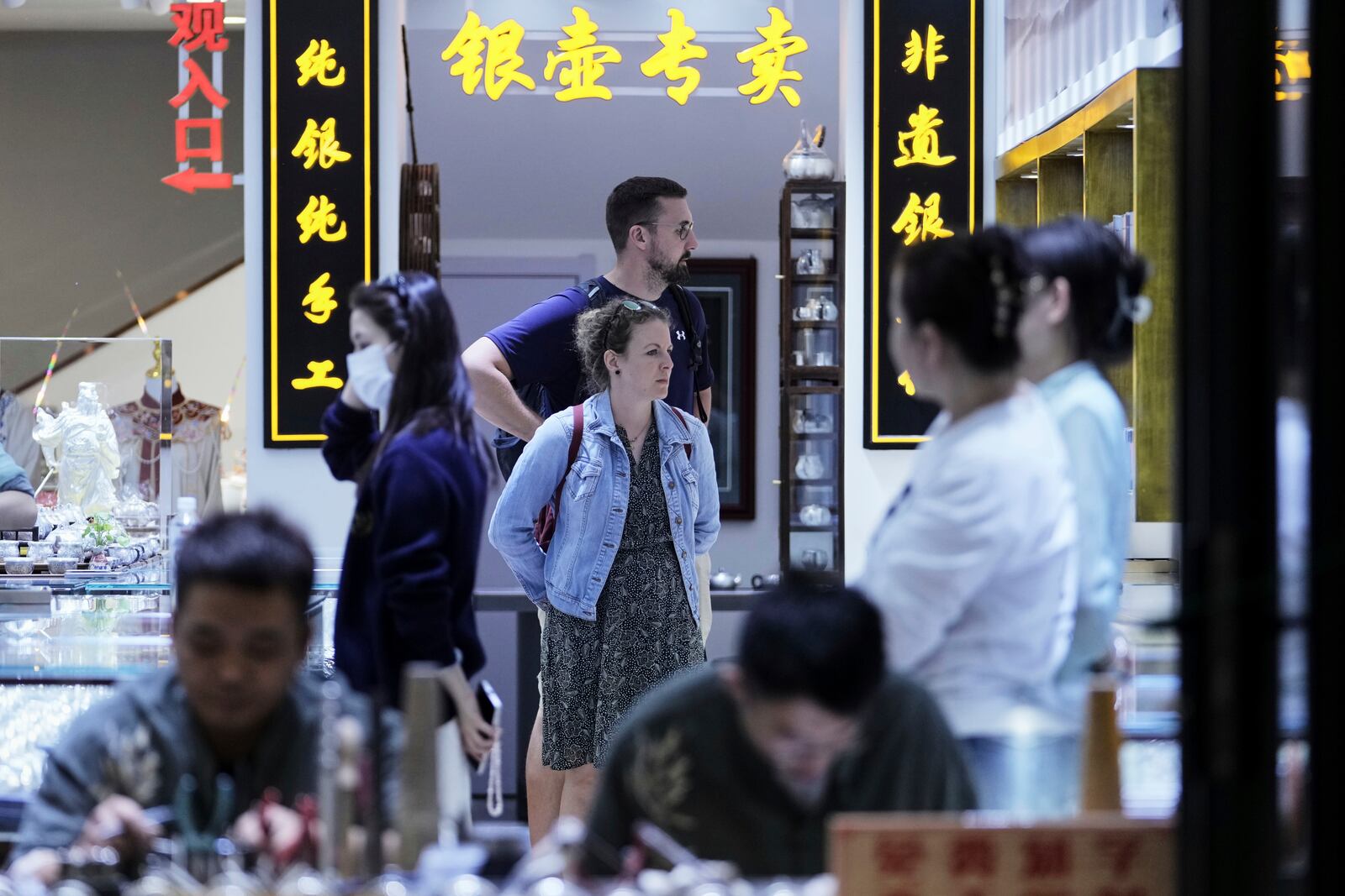 A tourist couple visit a souvenir store at Qianmen pedestrian shopping street in Beijing, Sunday, April 27, 2025. (AP Photo/Andy Wong)