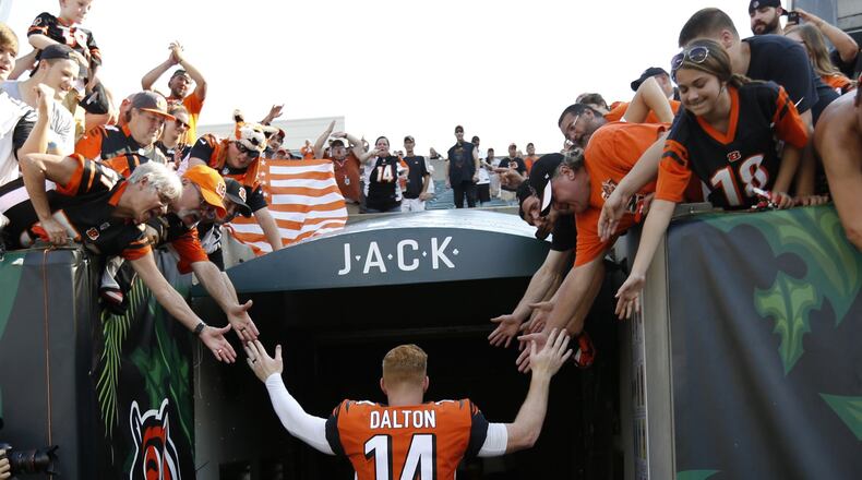 FILE - In this Oct. 7, 2018, file photo, Cincinnati Bengals quarterback Andy Dalton (14) high-fives fans as he leaves the field following an NFL football game against the Miami Dolphins in Cincinnati. The Bengals cleared the way for Joe Burrow to lead the team by releasing quarterback Andy Dalton, who holds several of the franchise’s passing records but couldn’t lead the woebegone Bengals deep into the playoffs. The move Thursday, April 30, 2020, gives Dalton, who had a year left on his deal, a chance to compete for a job with another team. (AP Photo/Frank Victores, File)
