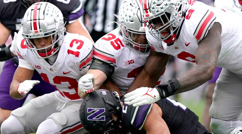 Northwestern running back Evan Hull, bottom, is tackled by Ohio State safety Cameron Martinez, left, linebacker Tommy Eichenberg and defensive end Zach Harrison, right, during the second half of an NCAA college football game, Saturday, Nov. 5, 2022, in Evanston, Ill. (AP Photo/Nam Y. Huh)