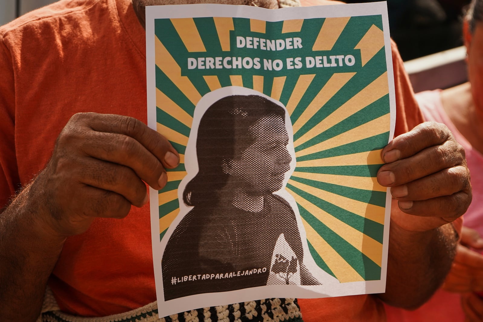 A man holds a poster of Alejandro Henriquez outside the courts during their hearing in Santa Tecla, El Salvador, Friday, May 30, 2025. The National Civil Police arrested them for protesting near the presidnetial residence. (AP Photo/Salvador Melendez)