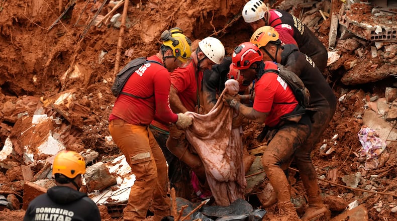 Firefighters recover a body from the site where homes collapsed during heavy rains and severe flooding in the Parque Burnier neighborhood of Juiz de Fora, Minas Gerais state, Brazil, Tuesday, Feb. 24, 2026. (AP Photo/Silvia Izquierdo)
