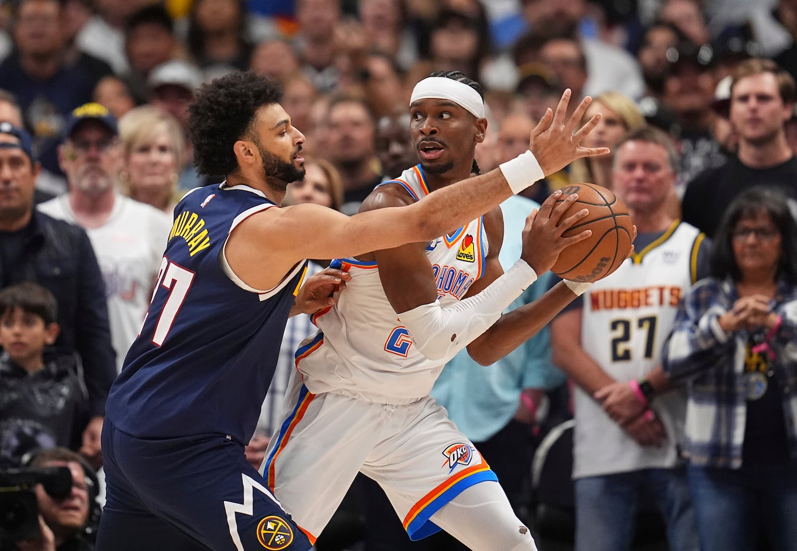 Oklahoma City Thunder guard Shai Gilgeous-Alexander, right, looks to pass the ball as Denver Nuggets guard Jamal Murray, left, defends in the first half of Game 4 in the Western Conference semifinals of the NBA basketball playoffs Sunday, May 11, 2025, in Denver. (AP Photo/David Zalubowski)