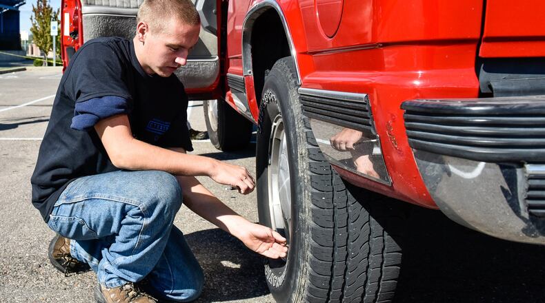 Gage Hacker, a Hamilton High School junior in the Career Technical Education Automotive Technology program, checks tire pressure on a student vehicle as students and AAA team up for safety checks on cars Tuesday, Oct. 3 at Hamilton High School in Hamilton. NICK GRAHAM/STAFF