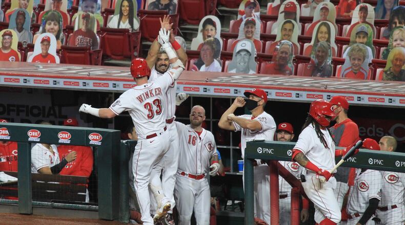 Jesse Winker and Eugenio Suarez, of the Reds, celebrate after Winker's home run against the Brewers on Wednesday, Sept. 23, 2020, at Great American Ball Park in Cincinnati. David Jablonski/Staff